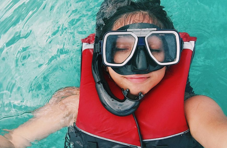 woman wearing a life jacket and a snorkeling mask taking a selfie while afloat